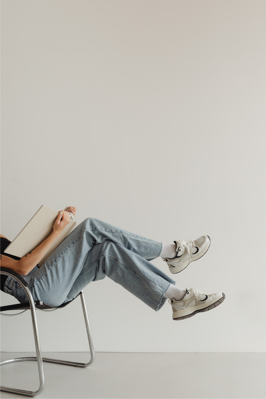 woman in light colored jeans with books